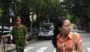 A plainclothes and a uniformed police officer stand in front of a court in Hanoi. Reuters