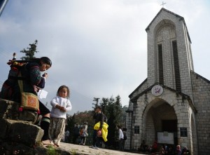 A Hmong woman sells souvenirs in front of a church in Sapa in Vietnam's northern highlands.  AFP PHOTO