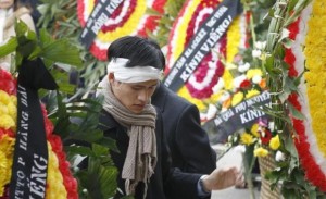 Nguyen Tien Trung stands between wreaths during a funeral for Hoang Minh Chinh in Hanoi