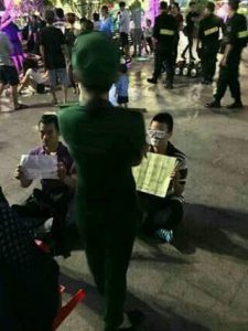 Activists Lau Nhat Phong and Mac Vi Luc sitting on street before being detained by HCMC police (photo from blogger Trang Nguyen)