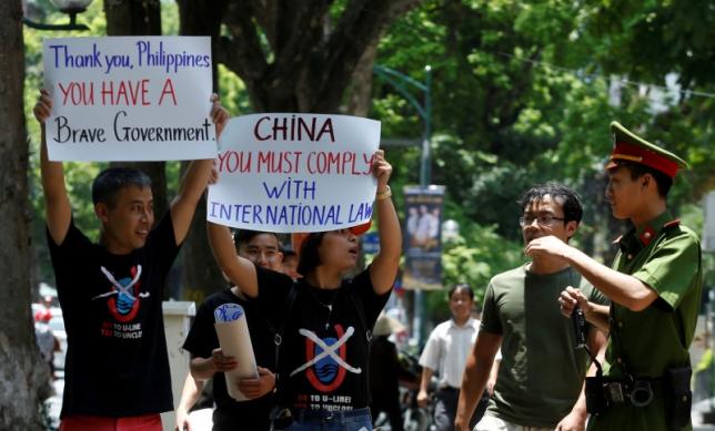 A policeman tries to stop anti-China protesters holding placards during a demonstration in front of the Philippines embassy in Hanoi, Vietnam July 17, 2016. REUTERS/KHAM